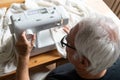 Old male man senior sit next at table at home work, sewing machine enjoy Royalty Free Stock Photo