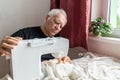 Old male man senior sit next at table at home work, sewing machine enjoy Royalty Free Stock Photo