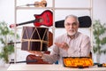 Old male repairman repairing musical instruments at workplace Royalty Free Stock Photo