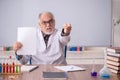 Old male teacher chemist sitting in the classroom