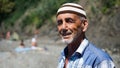 Old man on the beach. Cheerful man smiling and squinting enjoying vacation