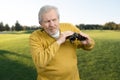 Old man with binoculars puzzled looking at sometning.