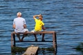 Old man and a boy sit on a self-made fishing platform with rods Royalty Free Stock Photo