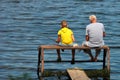 Old man and a boy sit on a self-made fishing platform with rods Royalty Free Stock Photo