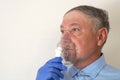 Old man breathing through an inhaler, portrait close-up Royalty Free Stock Photo