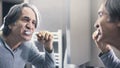 Old man brushing teeth in front of the mirror Royalty Free Stock Photo