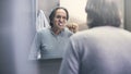 Old man brushing teeth in front of the mirror Royalty Free Stock Photo