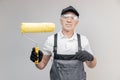 Old man builder painter in gloves and uniform holding painting roller repair apartment home