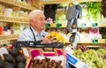 Old man cashier weighting banans at counter in greengrocer Royalty Free Stock Photo