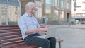 Old Man Celebrating Success on Laptop while Sitting Outdoor on Bench Royalty Free Stock Photo