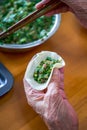 An old man in a Chinese family makes dumplings by hand