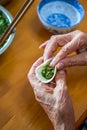 An old man in a Chinese family makes dumplings by hand