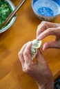 An old man in a Chinese family makes dumplings by hand