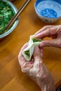 An old man in a Chinese family makes dumplings by hand