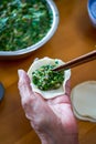 An old man in a Chinese family makes dumplings by hand