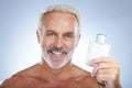 Old man, cologne aftershave and portrait in a studio with perfume and spray bottle product with a smile. Isolated, grey