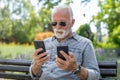 Old man compare two smartphones