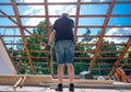 Old man is cutting out the frame of a new window in the roof of a private house. A do it yourself project Royalty Free Stock Photo