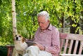 Old man with dog and tablet in garden Royalty Free Stock Photo