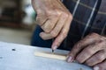 Old man drilling a wood strip with a gimlet