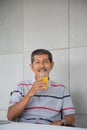 Old man drink orange juice for healthy in his work room