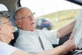 Old man driving car while checking map