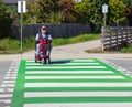 Old man driving a mobility scooter wheelchair crossing the street on a zebra