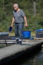 Old man fish farm worker carries bucket Royalty Free Stock Photo