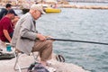 Old man fishing on a fishing rod in the sea, in the evening Royalty Free Stock Photo