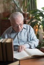 Old man in glasses reading a books in the room Royalty Free Stock Photo