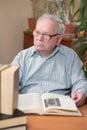 Old man in glasses reading a books in the room Royalty Free Stock Photo