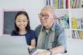 Old man and granddaughter use laptop in library Royalty Free Stock Photo