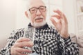 Old man having a glass of water and pills in hand