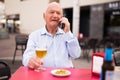 Old man having telephone conversation in outdoor cafe Royalty Free Stock Photo