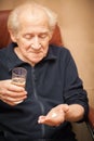 Old man holding a glass of water and pills Royalty Free Stock Photo