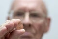 Old man holds in his hand a coin of two euro cent. Royalty Free Stock Photo