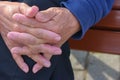 A old man holds his hands together while waiting or thinking for something.