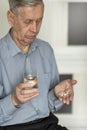 The old man holds pills and a glass of water in his hands. Royalty Free Stock Photo