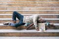 Old man homeless sleeping on stairs in urban