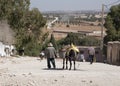 An old man leading his grocery laden donkey away from the weekly berber open market a short way from Essaouira in Morocco - Landsc