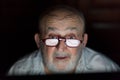 Old man looking at computer screen with profit line reflection on his glasses Royalty Free Stock Photo