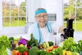 Old man making vegetables juice in the kitchen