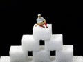 old man in miniature sitting on sugar cubes, concept image of increasing sugar consumption in old age