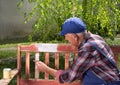 Old man painting bench in garden Royalty Free Stock Photo