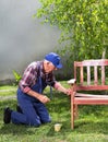 Old man painting bench in garden Royalty Free Stock Photo