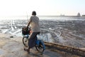 Old man pedaling his bicycle on the beach in Surabaya, Indonesia