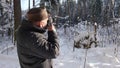 old man is photographing nature in snowy winter forest at sunny weather, photographer is taking picture Royalty Free Stock Photo