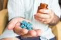 Old man with a pile of blue pills in his hand