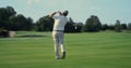 Old man play golf on grass fairway. Pro player swing club hitting ball outside. Royalty Free Stock Photo