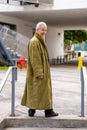 Old man posing in a green oversize trenchcoat